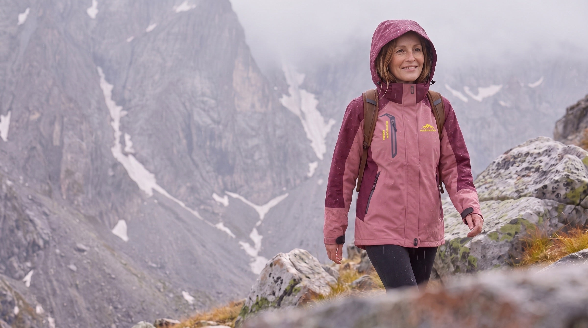 Wandelaarster in een waterdichte jas in de regen op een bergpad