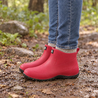 Korte regenlaarzen dames in fuchsia gedragen op een nat bospad in de herfst