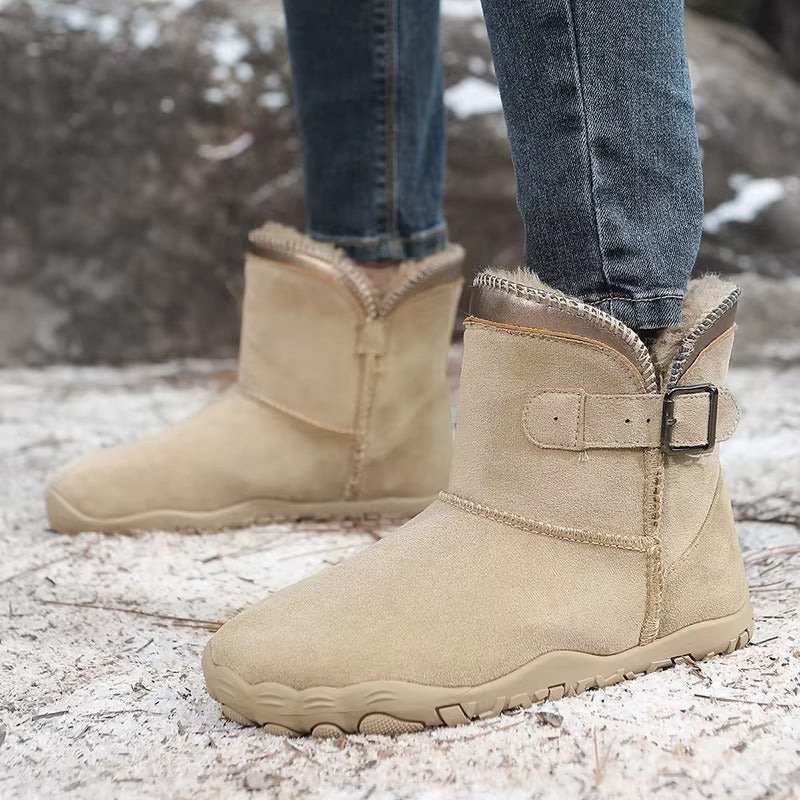 Gevoerde laarzen in zandbeige gedragen op besneeuwde grond